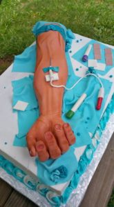 A cake that looks like an arm that is getting blood drawn